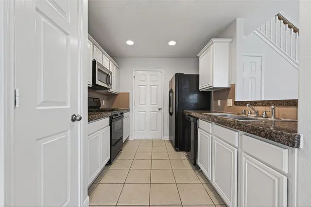 a kitchen with granite countertop a stove top oven sink and cabinets