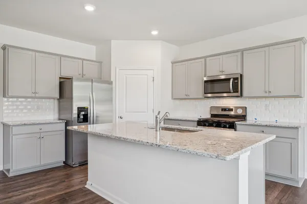 a kitchen with granite countertop a refrigerator sink and white cabinets