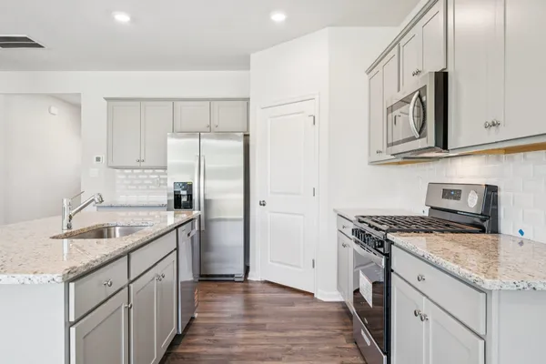 a kitchen with stainless steel appliances granite countertop a sink stove and refrigerator