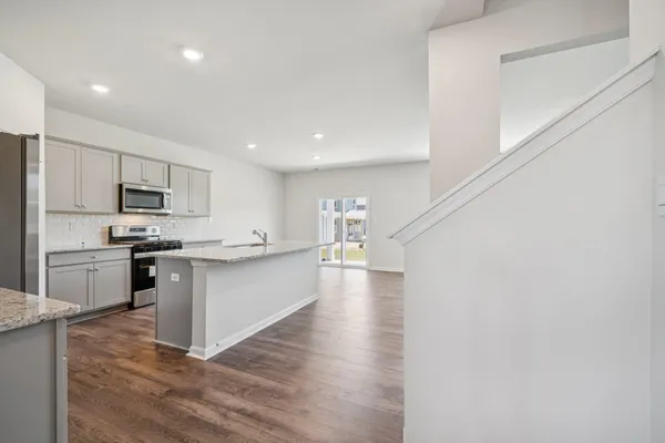 a kitchen with granite countertop a stove a sink and a refrigerator
