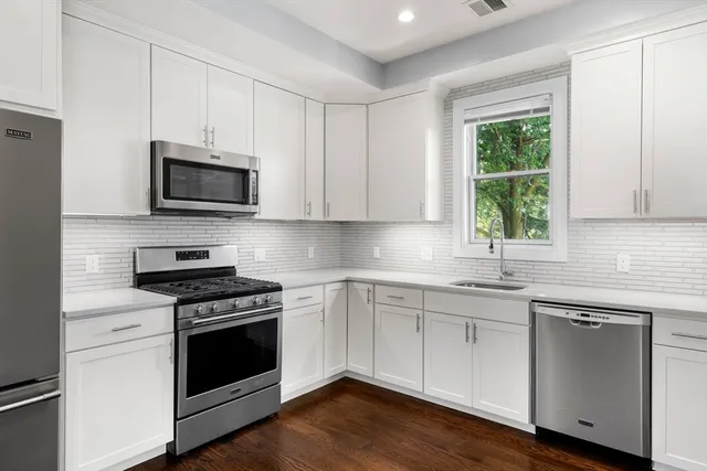 a kitchen with cabinets stainless steel appliances a sink and a window