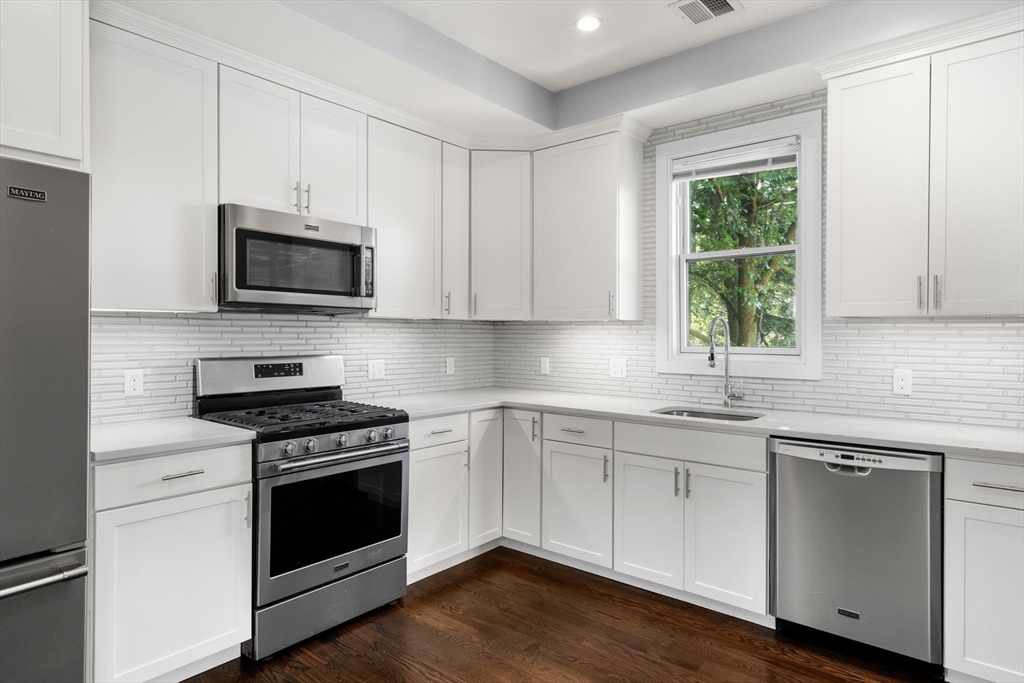 a kitchen with cabinets stainless steel appliances a sink and a window