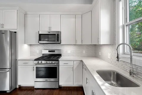 a kitchen with white cabinets sink and stainless steel appliances