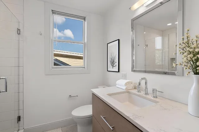 a bathroom with a granite countertop sink a toilet and a mirror
