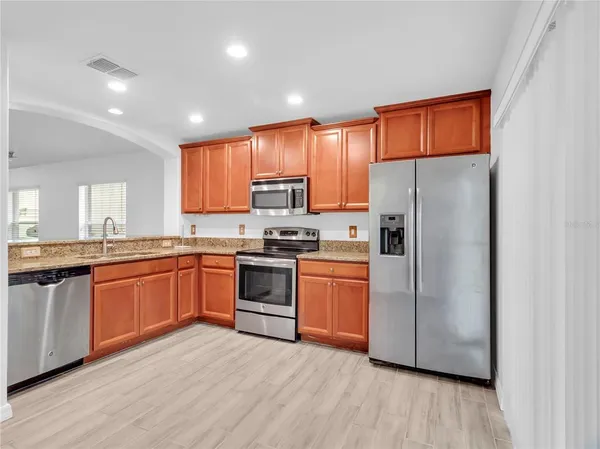 a kitchen with granite countertop stainless steel appliances a refrigerator cabinets and wooden floor