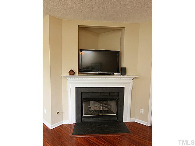 1127 Lake Moraine Place Raleigh, NC 27607 - Photo 4 of 23 a living room with a fireplace and a flat screen tv