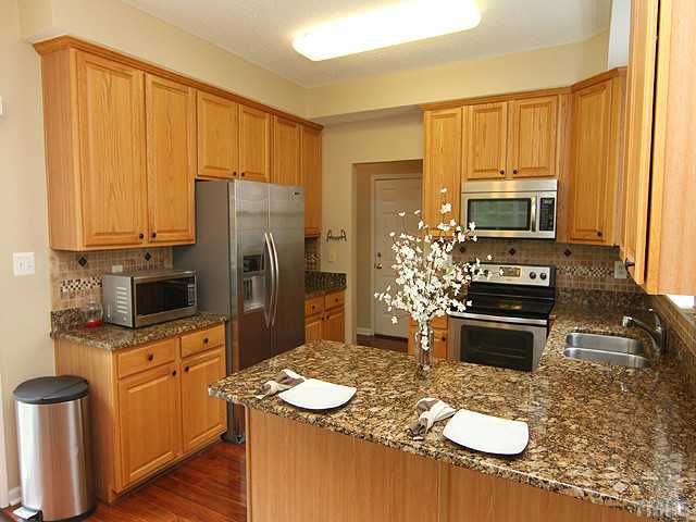 1127 Lake Moraine Place Raleigh, NC 27607 - Photo 9 of 23 a kitchen with kitchen island granite countertop a sink stove and refrigerator