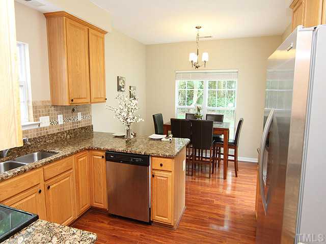 1127 Lake Moraine Place Raleigh, NC 27607 - Photo 10 of 23 a kitchen with stainless steel appliances granite countertop a stove top oven a dining table and chairs with wooden floor