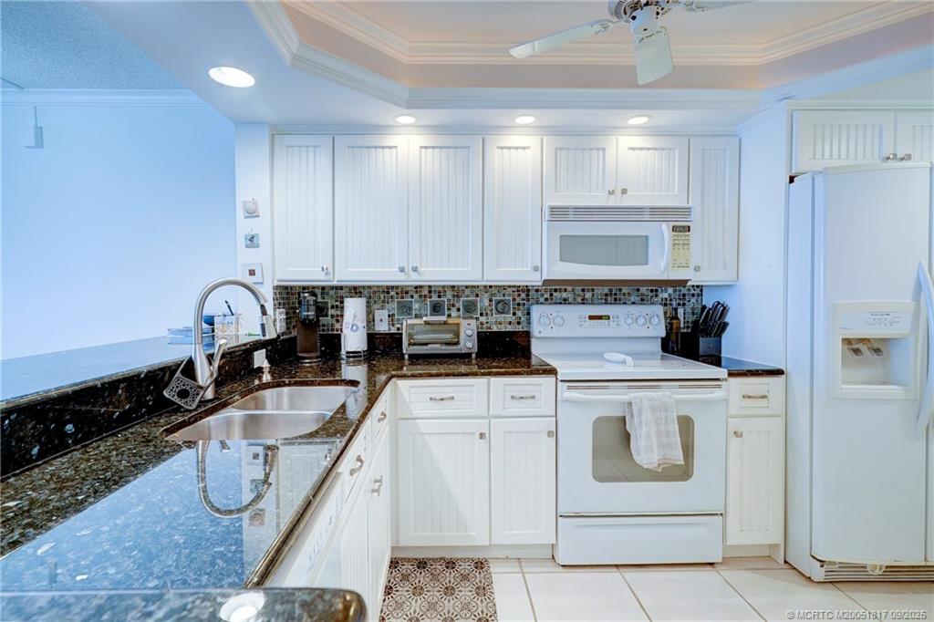 10 Northeast Plantation Road, Unit 203 Stuart, FL 34996 - Photo 14 of 50 a kitchen with white cabinets a sink and white appliances
