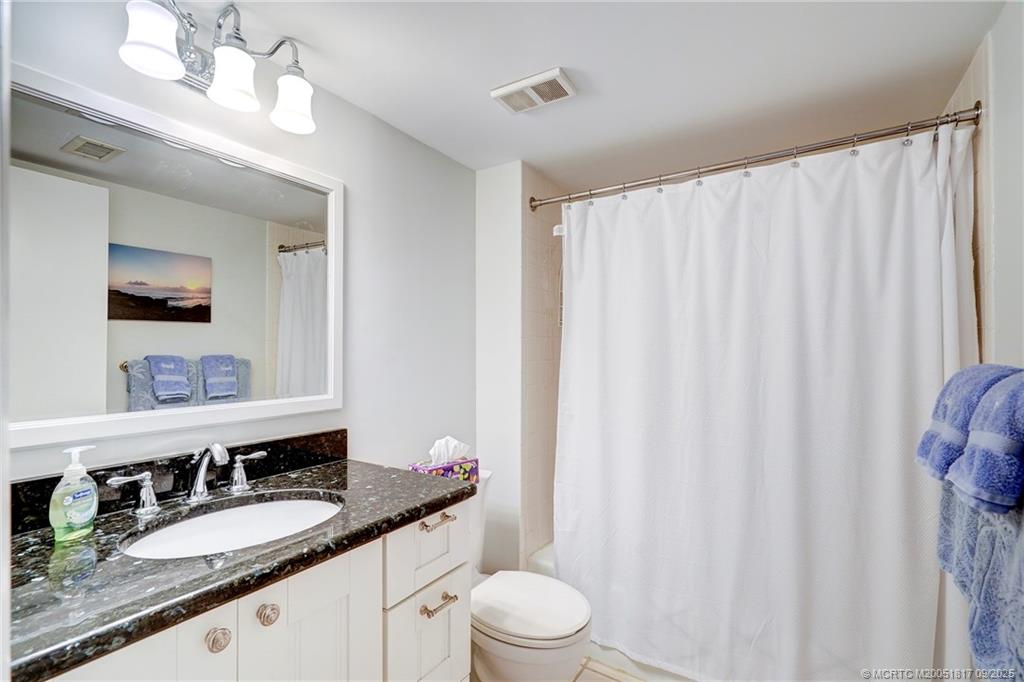 10 Northeast Plantation Road, Unit 203 Stuart, FL 34996 - Photo 18 of 50 a bathroom with a granite countertop sink a toilet and a mirror