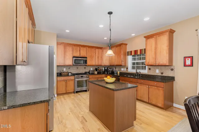 a kitchen with stainless steel appliances granite countertop a sink a stove a refrigerator a center island and cabinets