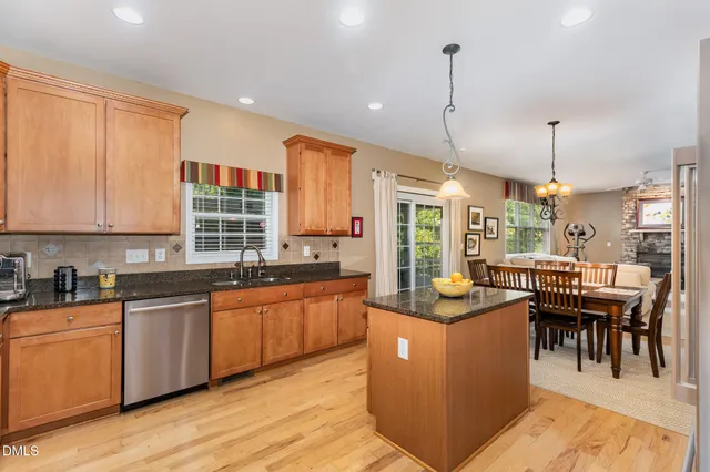 a kitchen with stainless steel appliances granite countertop wooden cabinets a dining table and chairs