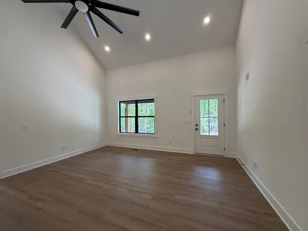 an empty room with wooden floor fan and windows