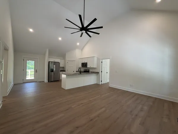 a view of empty room with wooden floor and ceiling fan