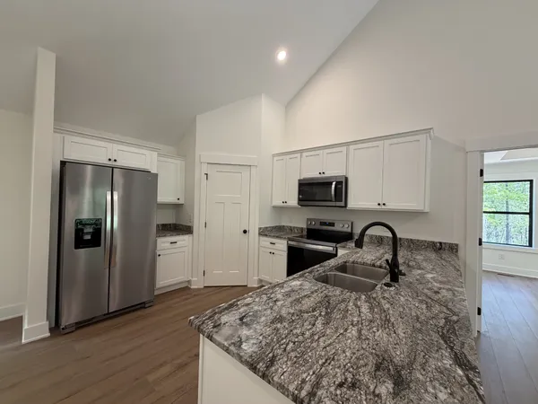 a kitchen with stainless steel appliances kitchen island granite countertop a refrigerator and a stove top oven