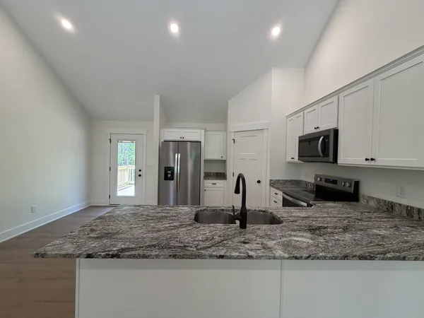 a kitchen with stainless steel appliances granite countertop a sink a stove and a refrigerator