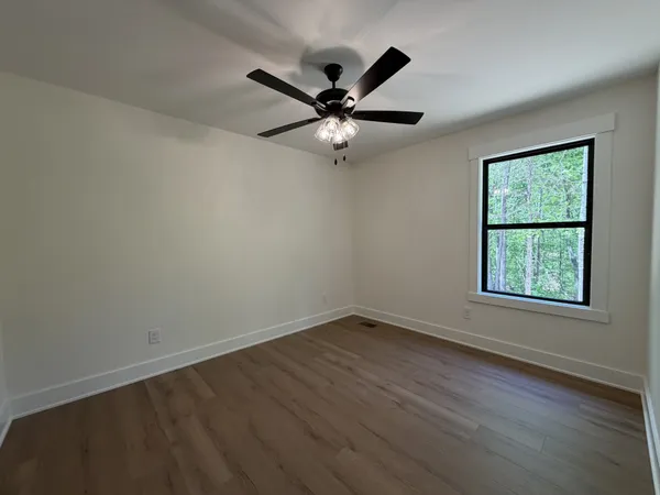 an empty room with wooden floor fan and windows