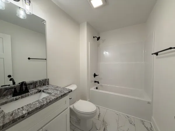 a bathroom with a granite countertop sink a toilet and shower