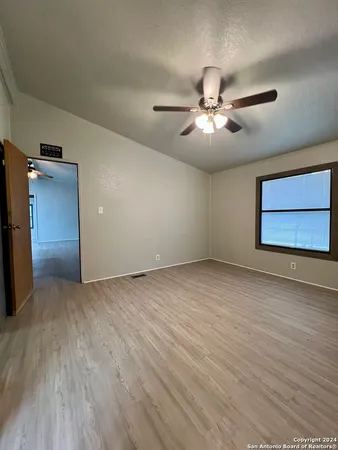 a view of an empty room and chandelier fan and windows