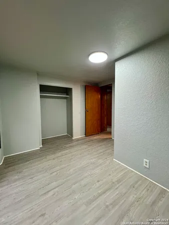 a view of an empty room with wooden floor and closet