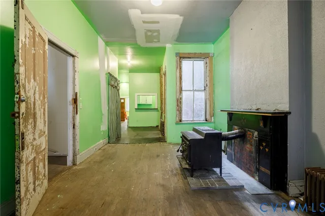 an empty room with wooden floor fireplace and windows