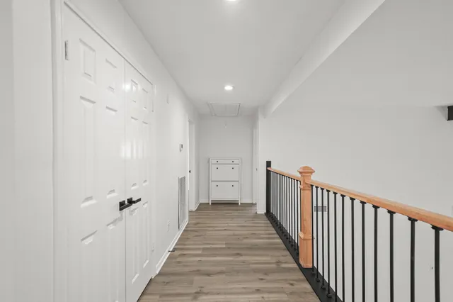 a view of a hallway with wooden floor and a bathroom