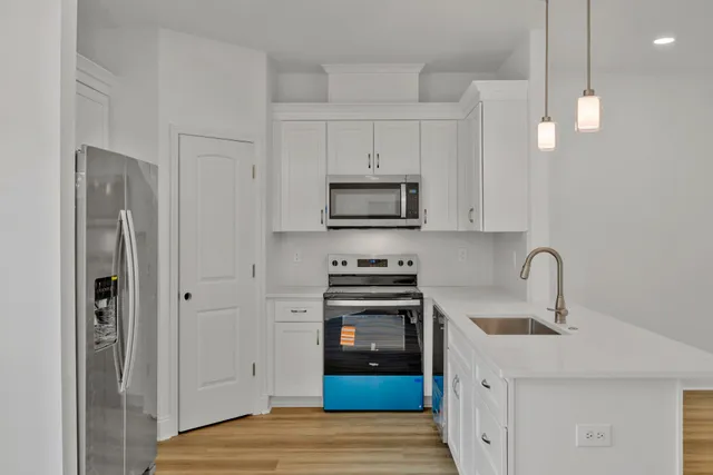 an empty room with wooden floor chandelier and windows
