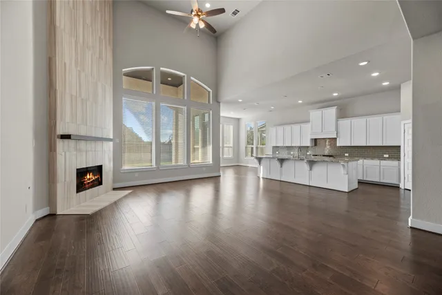 a view of an empty room with wooden floor and a kitchen