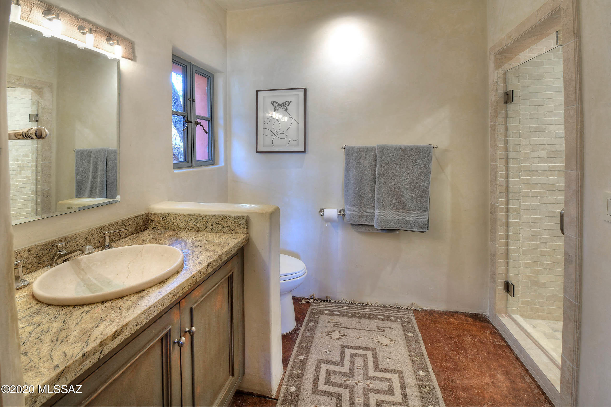 360 Harshaw Creek Road Patagonia, AZ 85624 - Photo 22 of 50 a bathroom with a granite countertop sink a mirror a vanity and a shower