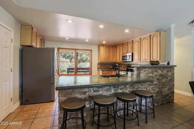 a kitchen with granite countertop a table chairs microwave and refrigerator