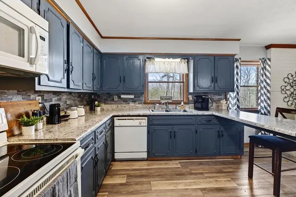 a kitchen with stainless steel appliances granite countertop a stove a sink and a microwave