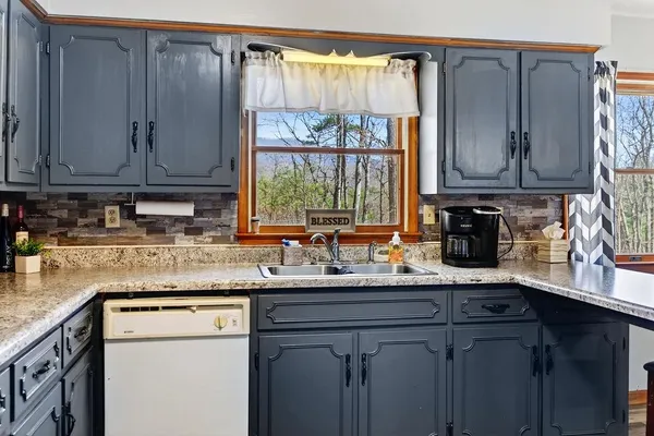 a kitchen with granite countertop a sink window and cabinets