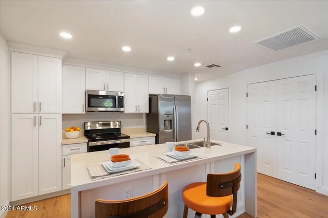 a kitchen with stainless steel appliances a stove a sink a refrigerator and cabinets