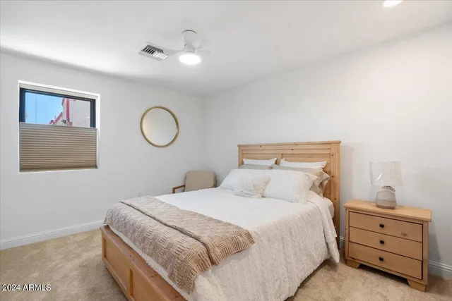 a bedroom with a bed and a lamp on dresser