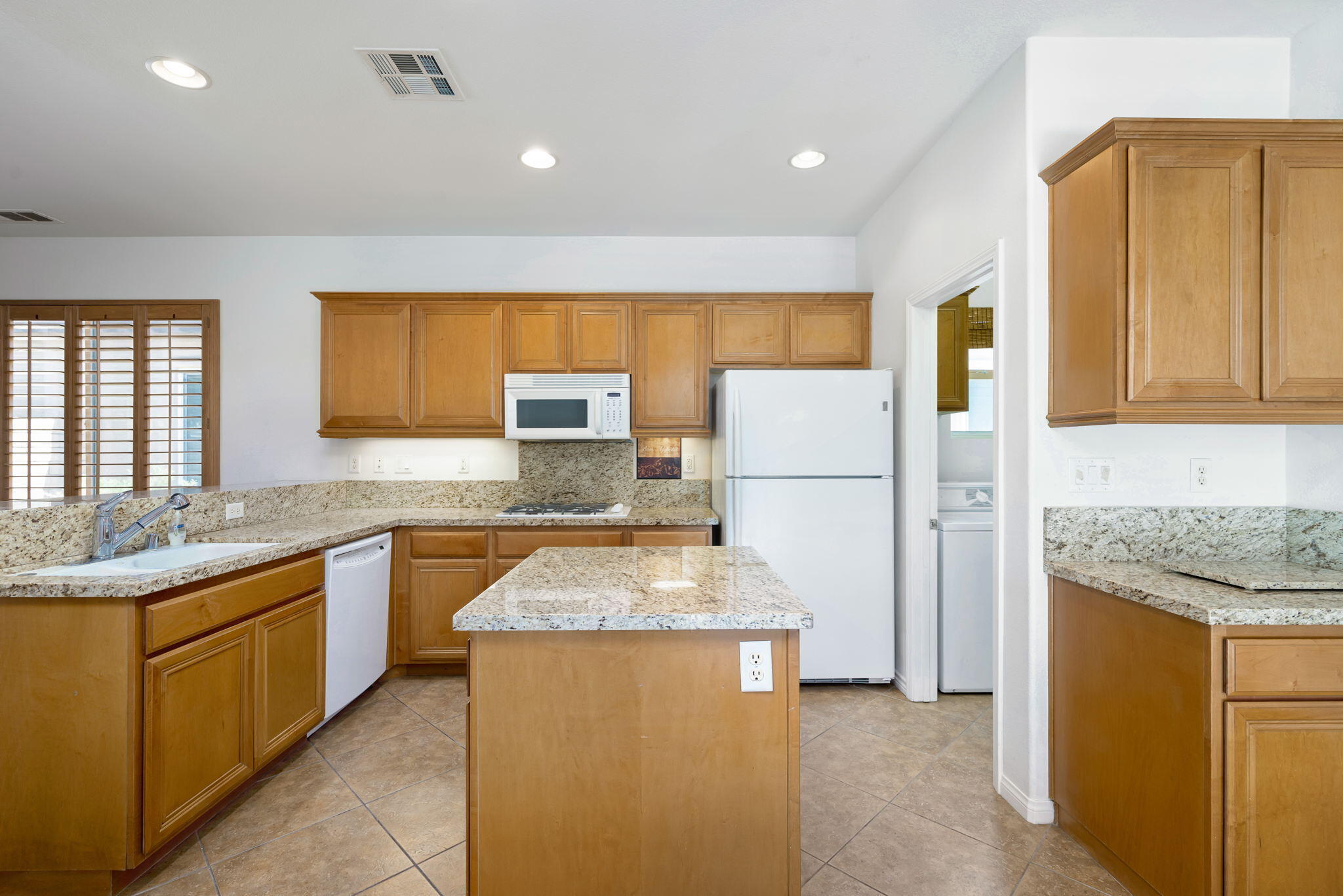 49728 Pacino Street Indio, CA 92201 - Photo 20 of 54 a kitchen with granite countertop sink refrigerator and cabinets