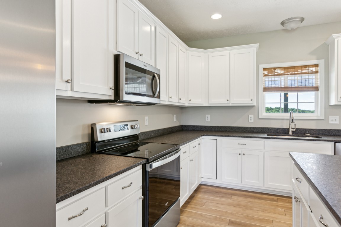 5129 Galen Road Lafayette, TN 37083 - Photo 8 of 25 a kitchen with granite countertop white cabinets stainless steel appliances and a window