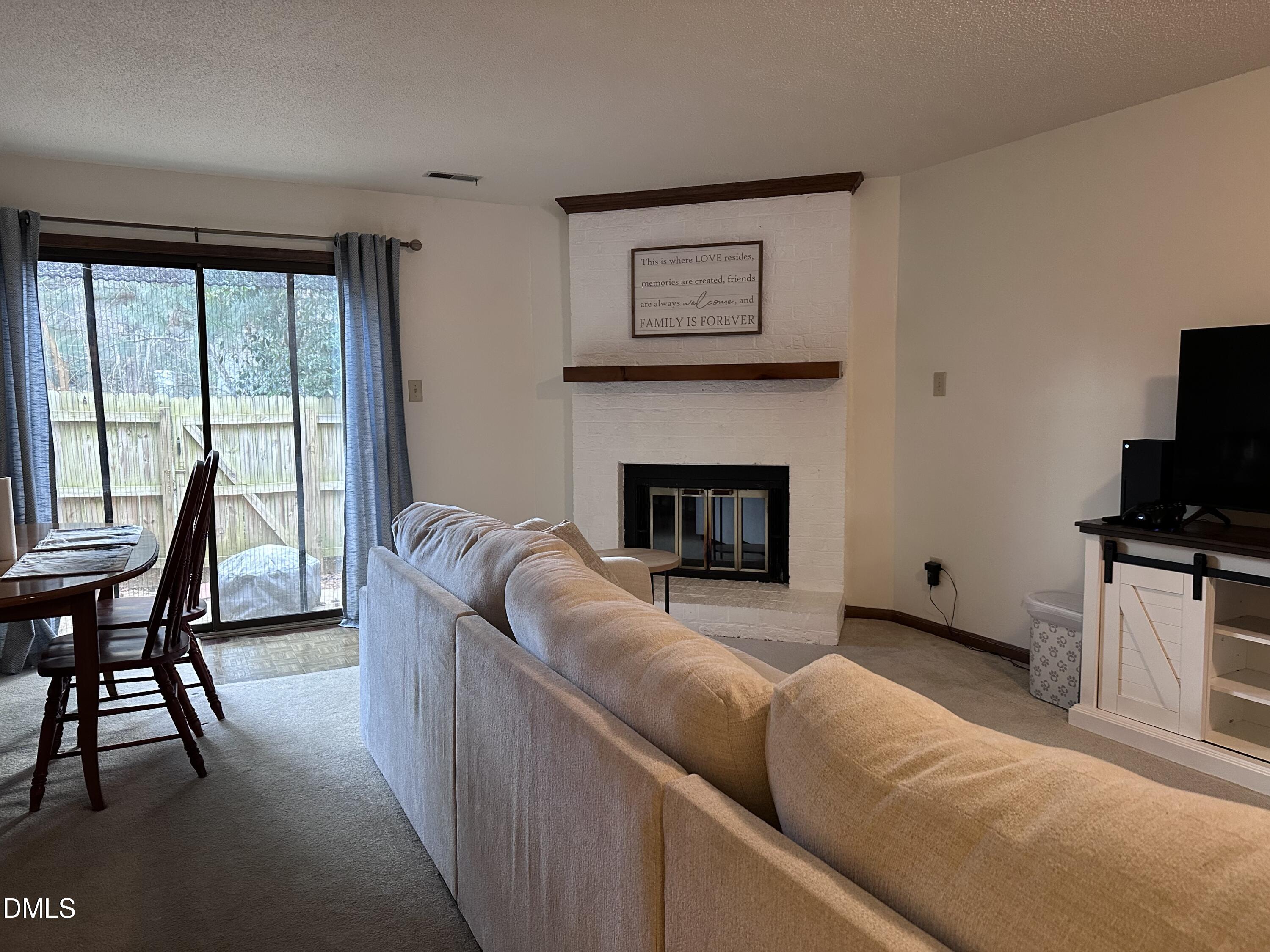 1440 Kent Road Raleigh, NC 27606 - Photo 4 of 21 a living room with furniture a fireplace and a flat screen tv
