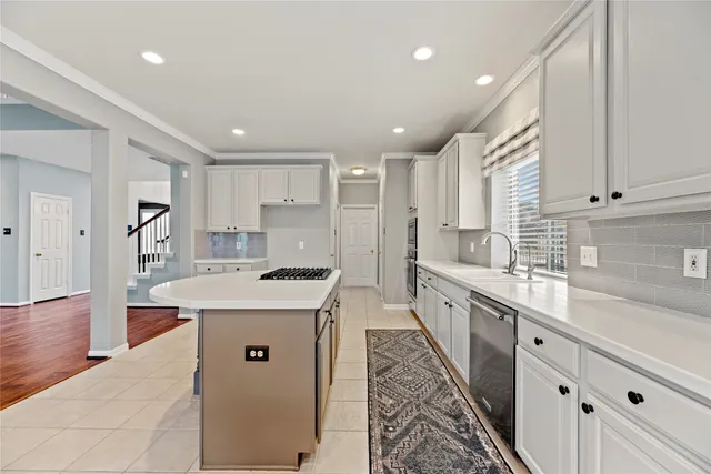 a large white kitchen with center island and stainless steel appliances