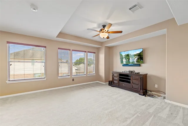 an empty room with windows and a chandelier fan
