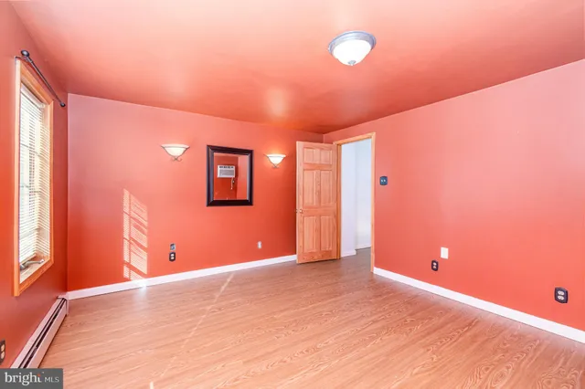 a view of an empty room with window and wooden floor