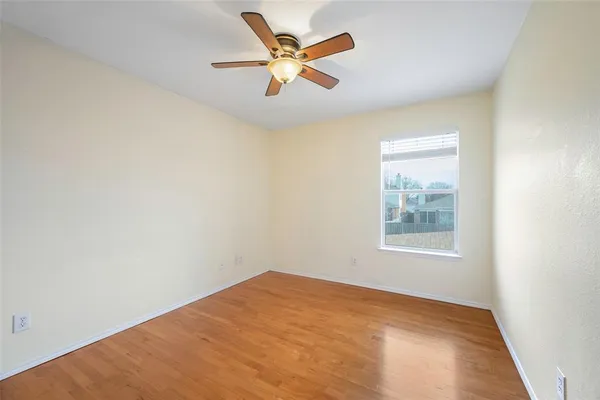 an empty room with a window and a ceiling fan