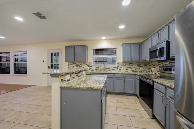 a large kitchen with granite countertop a stove sink and cabinets