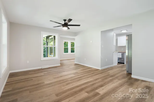 a view of an empty room with a window and wooden floor
