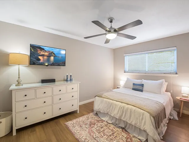 a bedroom with a large bed and a flat tv screen on dresser