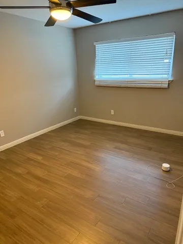 a view of an empty room with wooden floor and windows