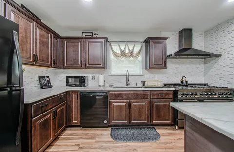 a kitchen with stainless steel appliances granite countertop a stove a sink dishwasher and cabinets with wooden floor