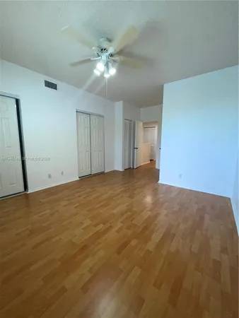 a view of an empty room and chandelier fan