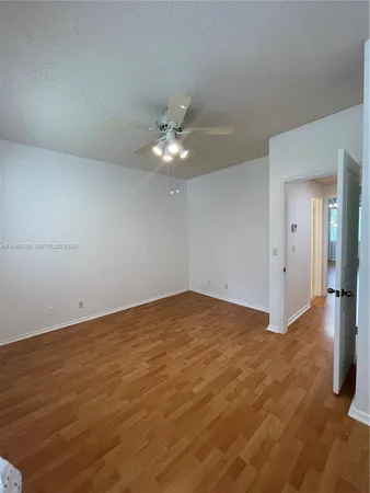 wooden floor in an empty room with a chandelier fan