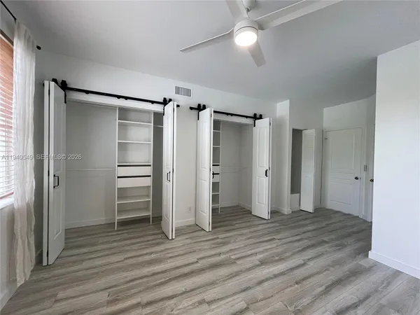 a view of empty room with wooden floor and window