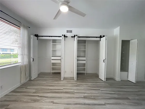 a view of walk in closet with wooden floor and fan